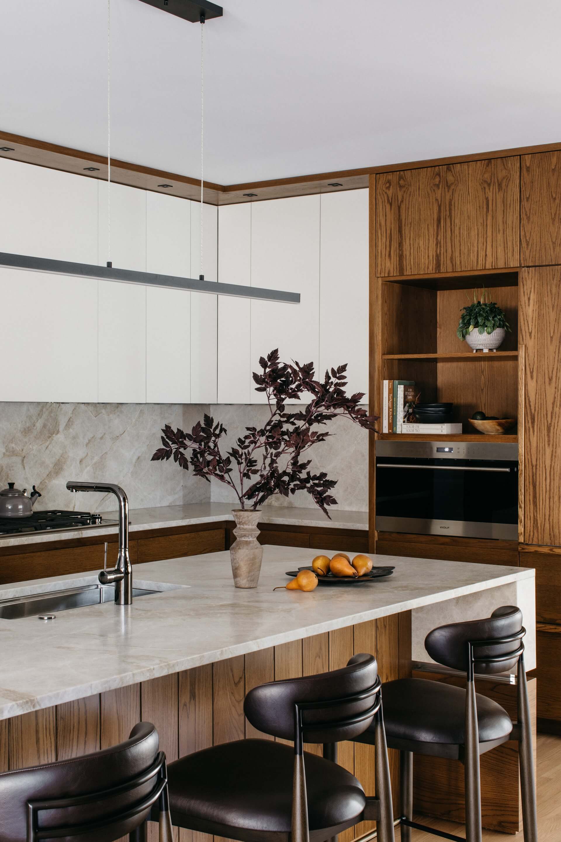 Modern kitchen remodeling features wood cabinetry, marble counters, pendant lighting, and a spacious island with seating.