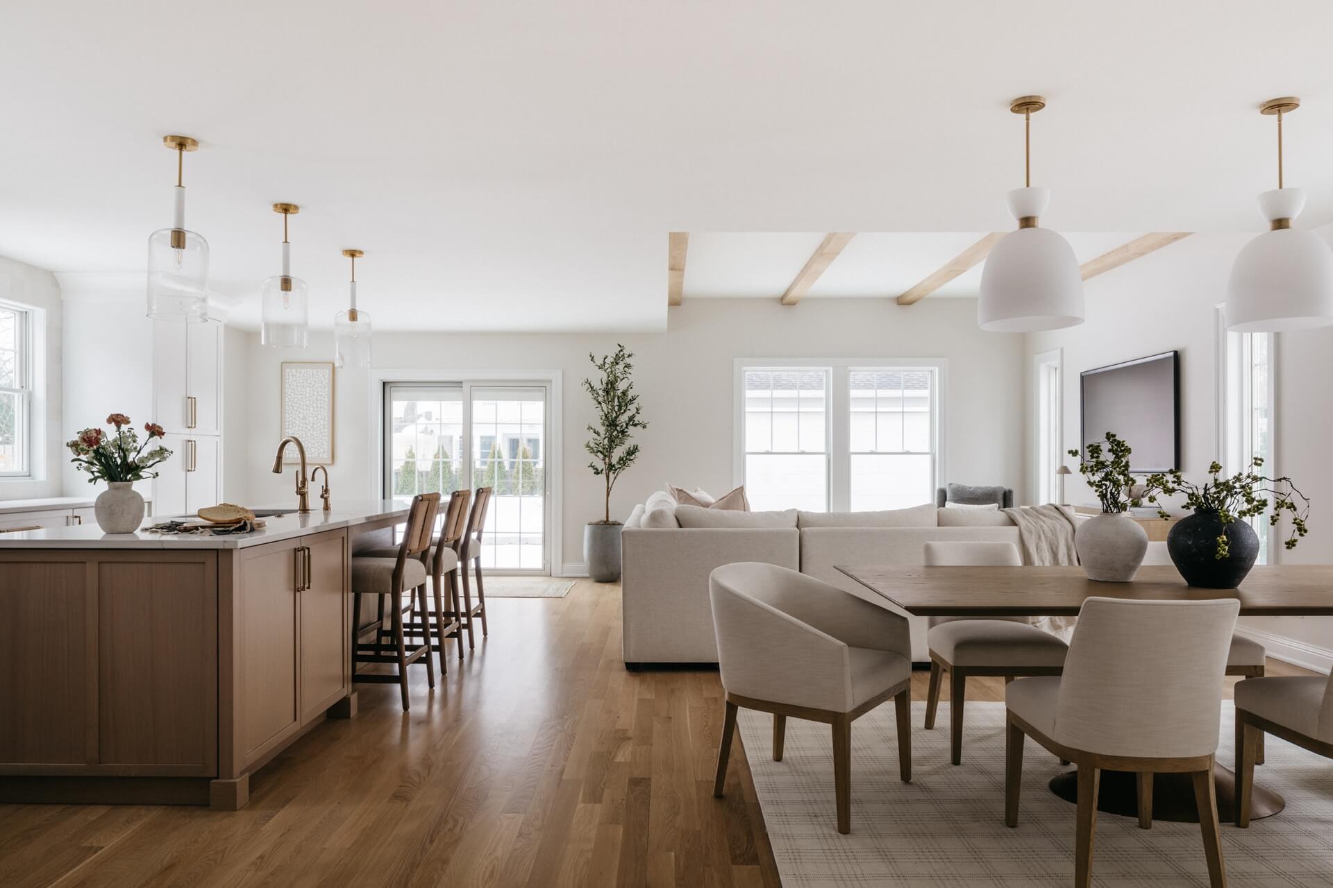 Bright open plan interior featuring a remodeled kitchen, dining area, living room, wood floors, and neutral furnishings.